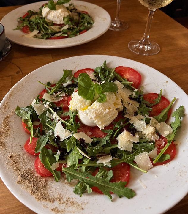 Burrata auf Tomatenscheiben mit Rucola und Grana