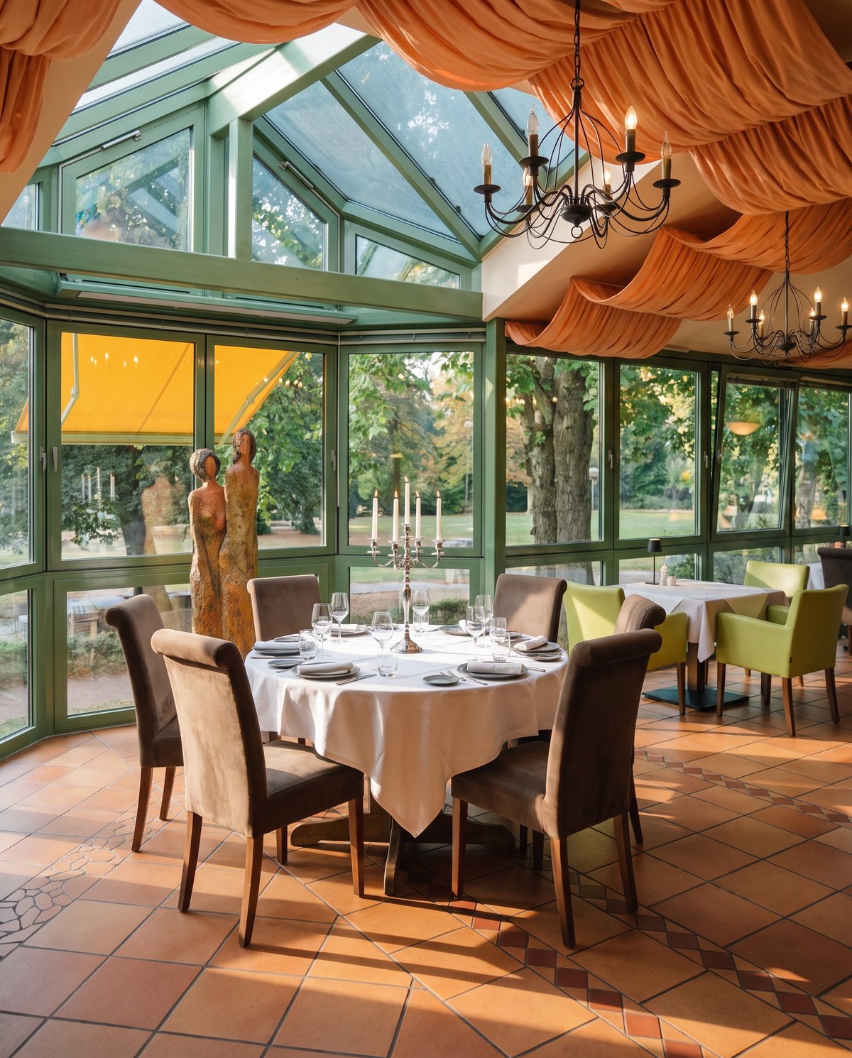 Runder, festlich gedeckter Tisch im Wintergarten des Ristorante Da Graziella mit Blick in den Oranienpark